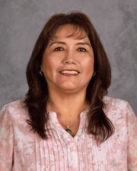 Portrait of a smiling woman in a pink blouse against a gray backdrop