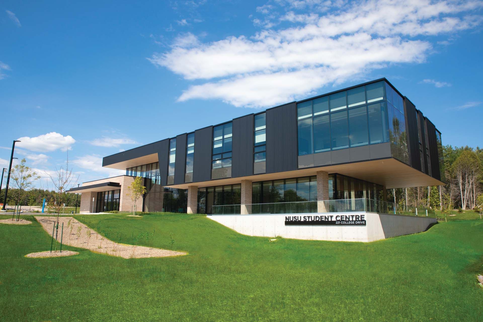 A large building with a lot of windows is sitting on top of a lush green field.