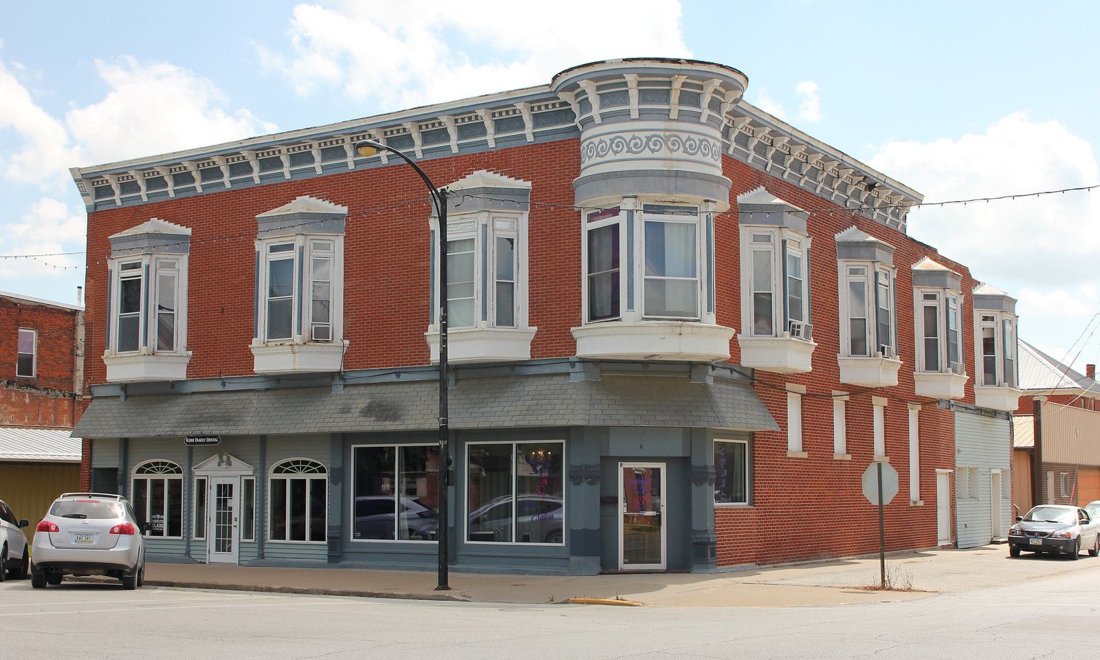 Two-story brick building with gray trim and large windows on a corner in Osceola, IA.