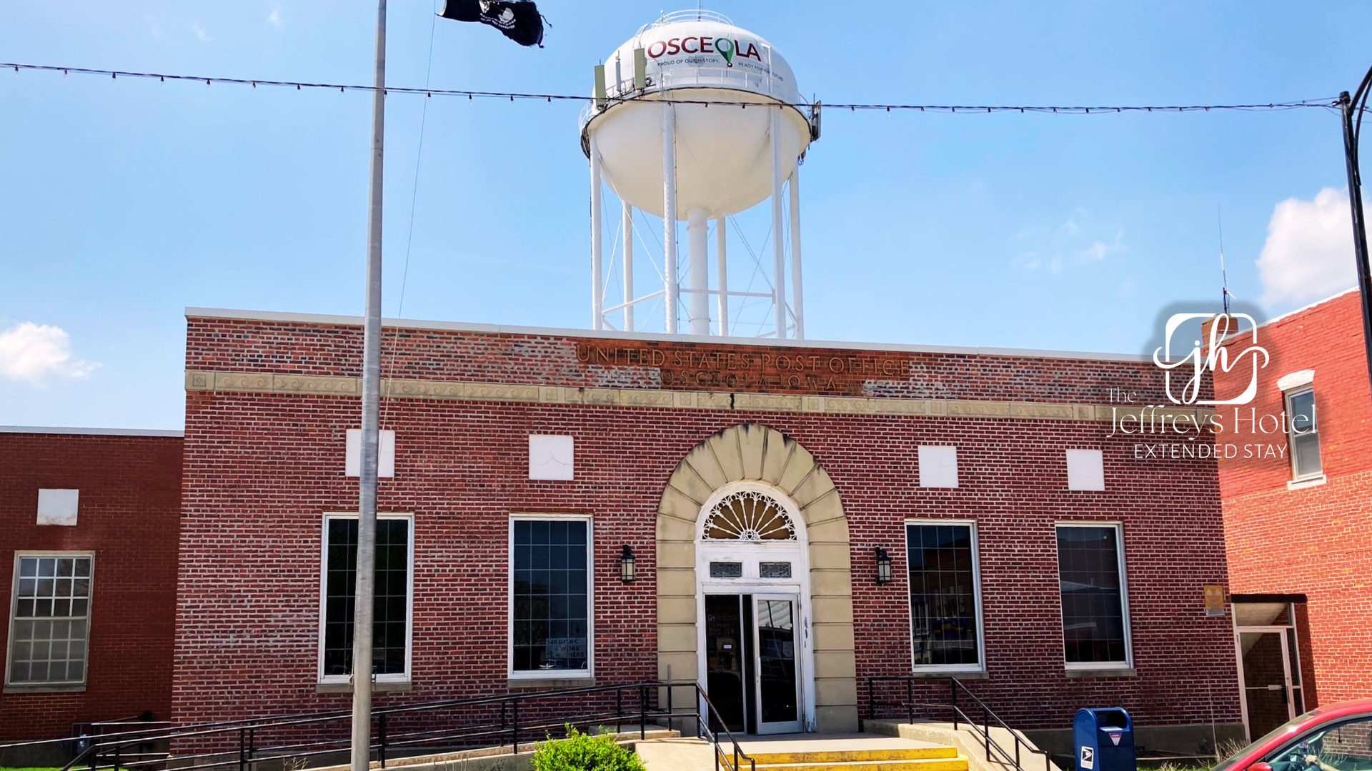 Brick building with arched doorway and water tower in background.