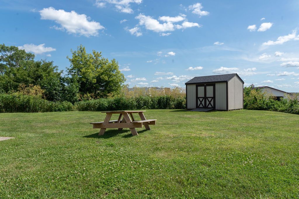 Picnic table on a grassy lawn with a shed under a blue sky.