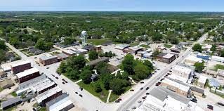 Aerial view of a small town Osceola, IA with a water tower, businesses, roads, and surrounding trees.
