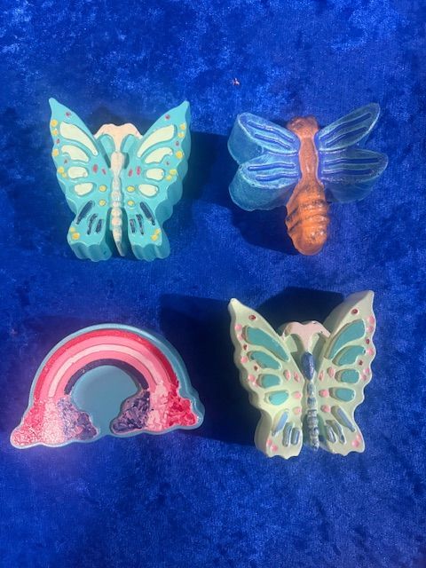 Four colorful butterfly-themed hair clips on a blue fuzzy background