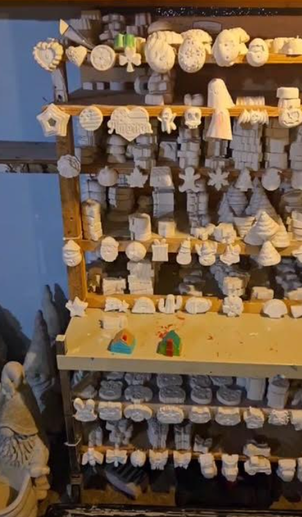 Shelves of small hanging ceramic ornaments and figurines in a craft shop display