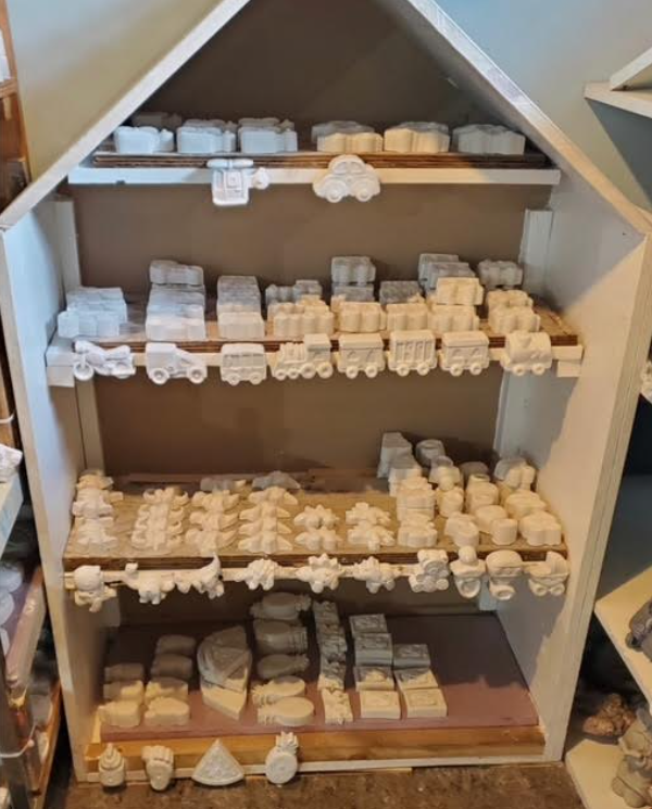 Wooden display shelf filled with rows of small white figurines and trinkets