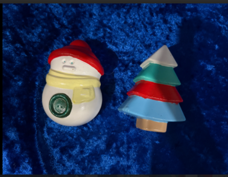 Small Santa figurine and colorful Christmas tree ornament on a blue plush background