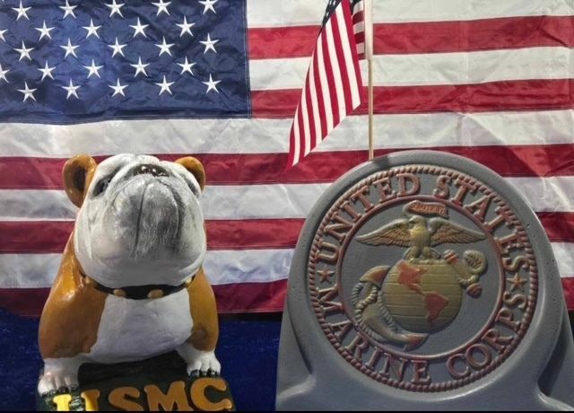 Bulldog figurine beside U.S. Marine Corps emblem in front of an American flag background