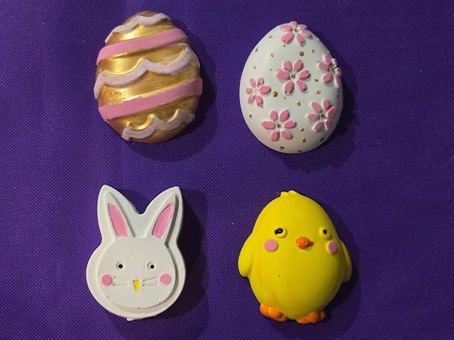 Four decorated pastel Easter cookies: two eggs, a bunny, and a chick on a purple background