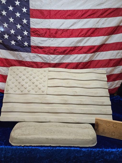 American flag backdrop with a small stone bench and step-like stone block on blue cloth.