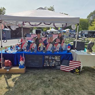 Outdoor booth with blue tablecloths, patriotic decorations, and two people behind a table at a park event