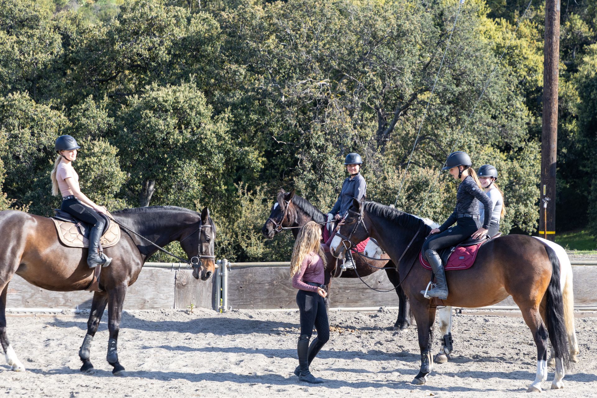 A group of people are riding horses in a fenced in area.