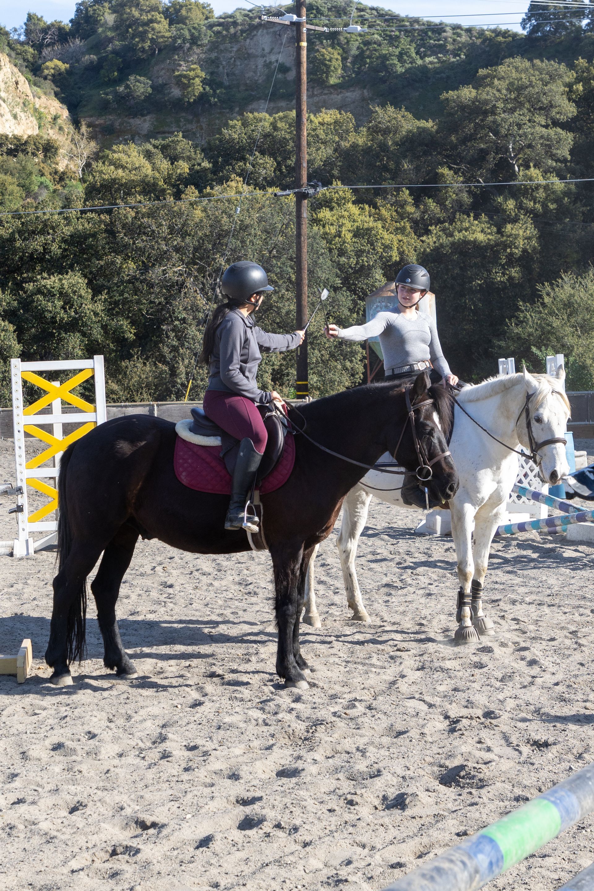 Two people are riding horses in a dirt field.