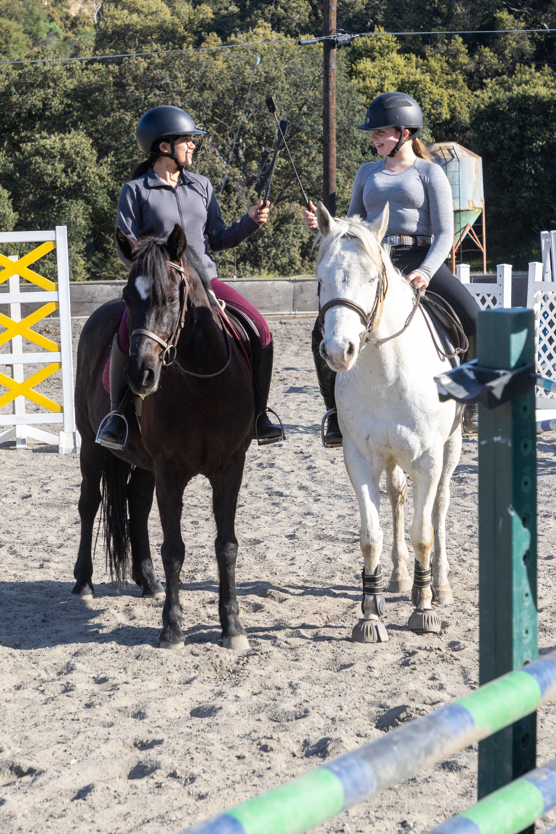 Two women are riding horses in a dirt arena