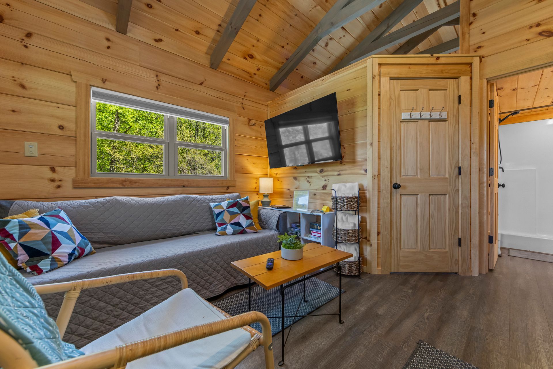 Cozy cabin living room with gray sofa, coffee table, wall-mounted TV, and wood-paneled interior