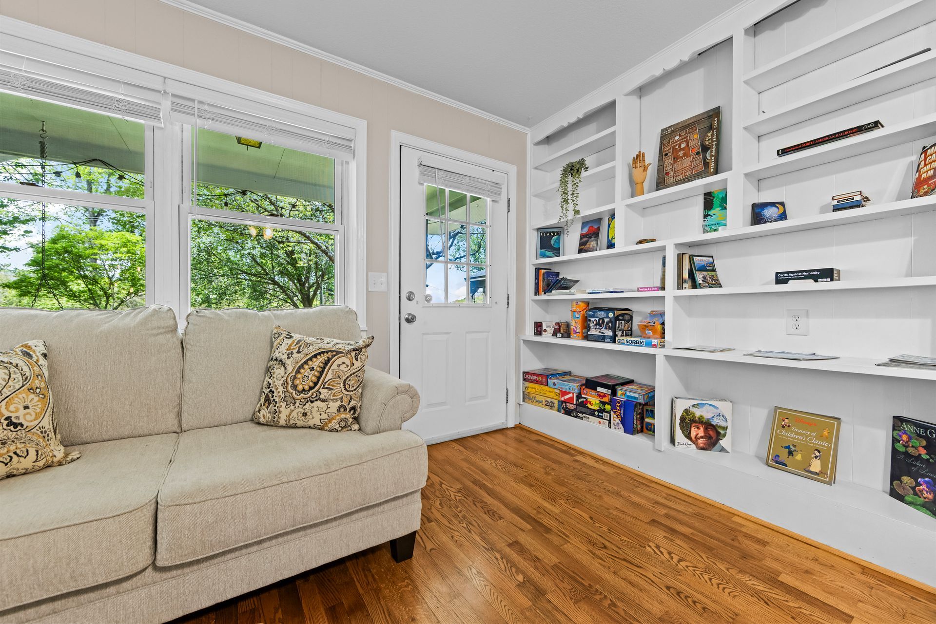 Bright living room with cream sofa, built-in white shelves, and warm wood floors.