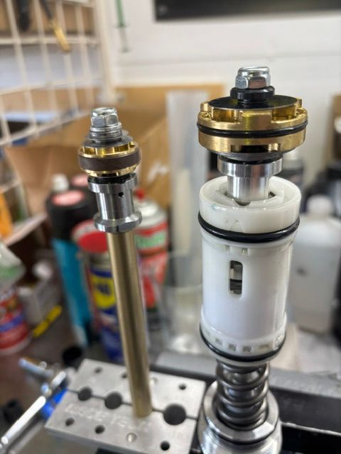 Close-up of two metal mechanical parts on a workbench, one with a white cylindrical casing.