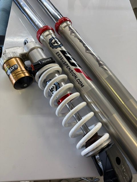 Two motorcycle shocks with chrome springs and red accents on a white surface