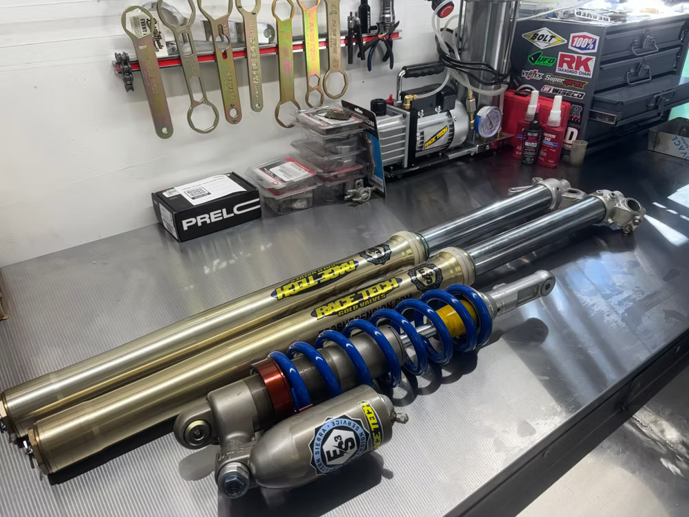 Suspension shocks and racing tools arranged on a workbench in a garage work area