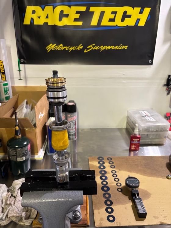 Motorcycle suspension parts on a workbench beneath a Race Tech banner