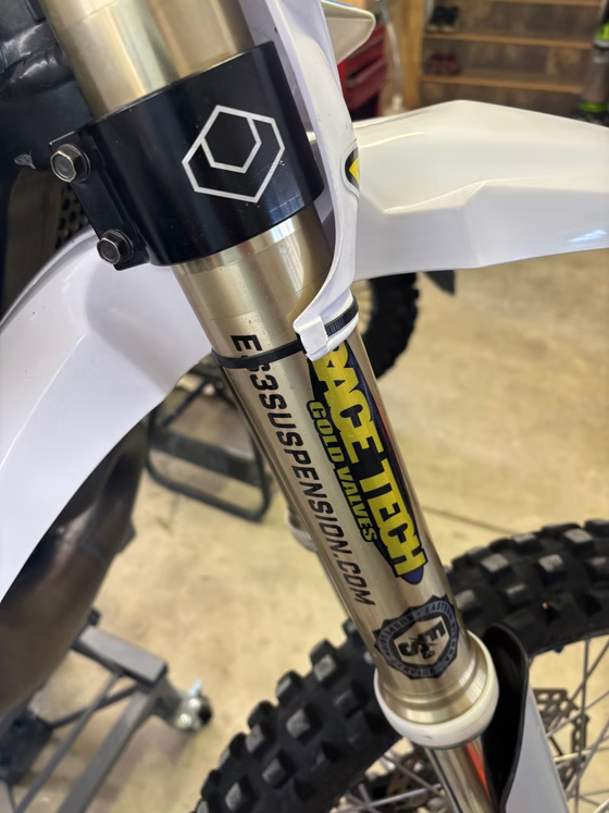 Close-up of a mountain bike’s front fork and frame with yellow and black decals.