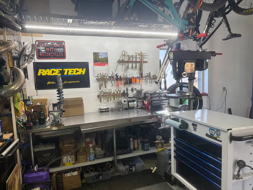 Bright workshop with CNC machine, workbench, tools, and Race Tech sign on the wall.