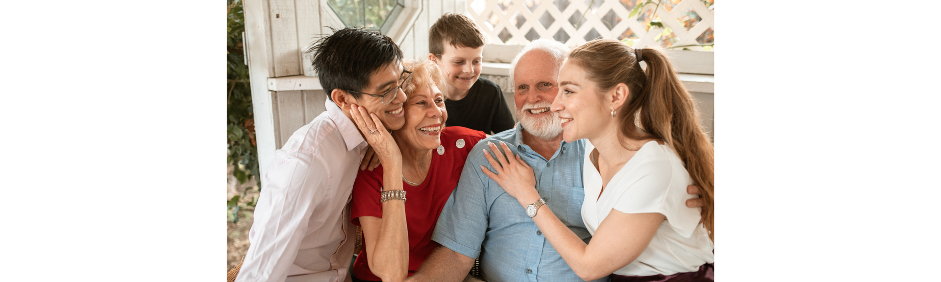 Family sitting together on a front porch, embracing & smiling, showing love, connection, & support.