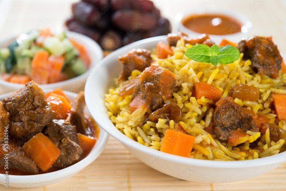 A bowl of rice with meat and carrots on a table.