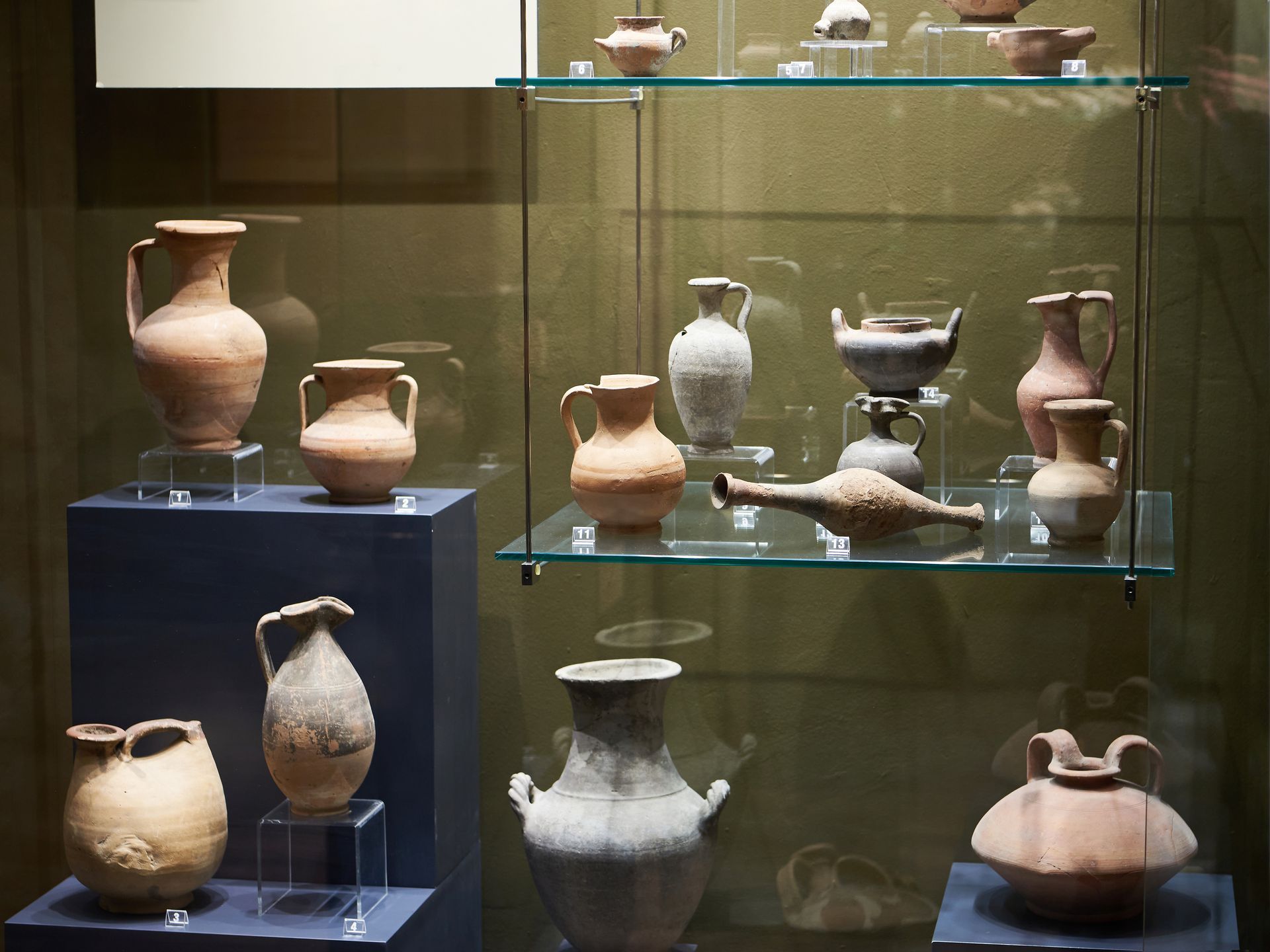 A collection of vases and pitchers on display in a glass case