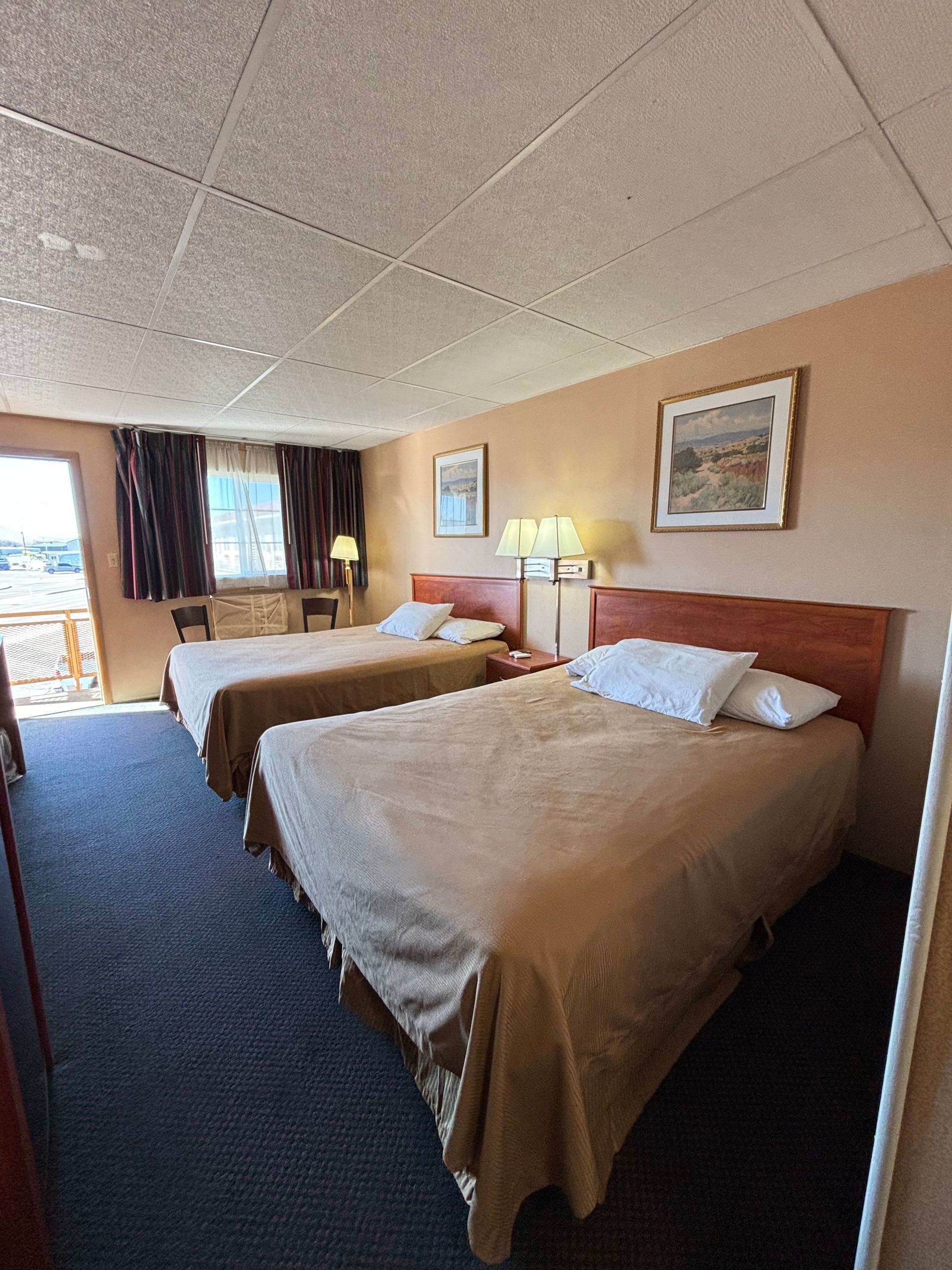 A hotel room with two beds and a balcony.