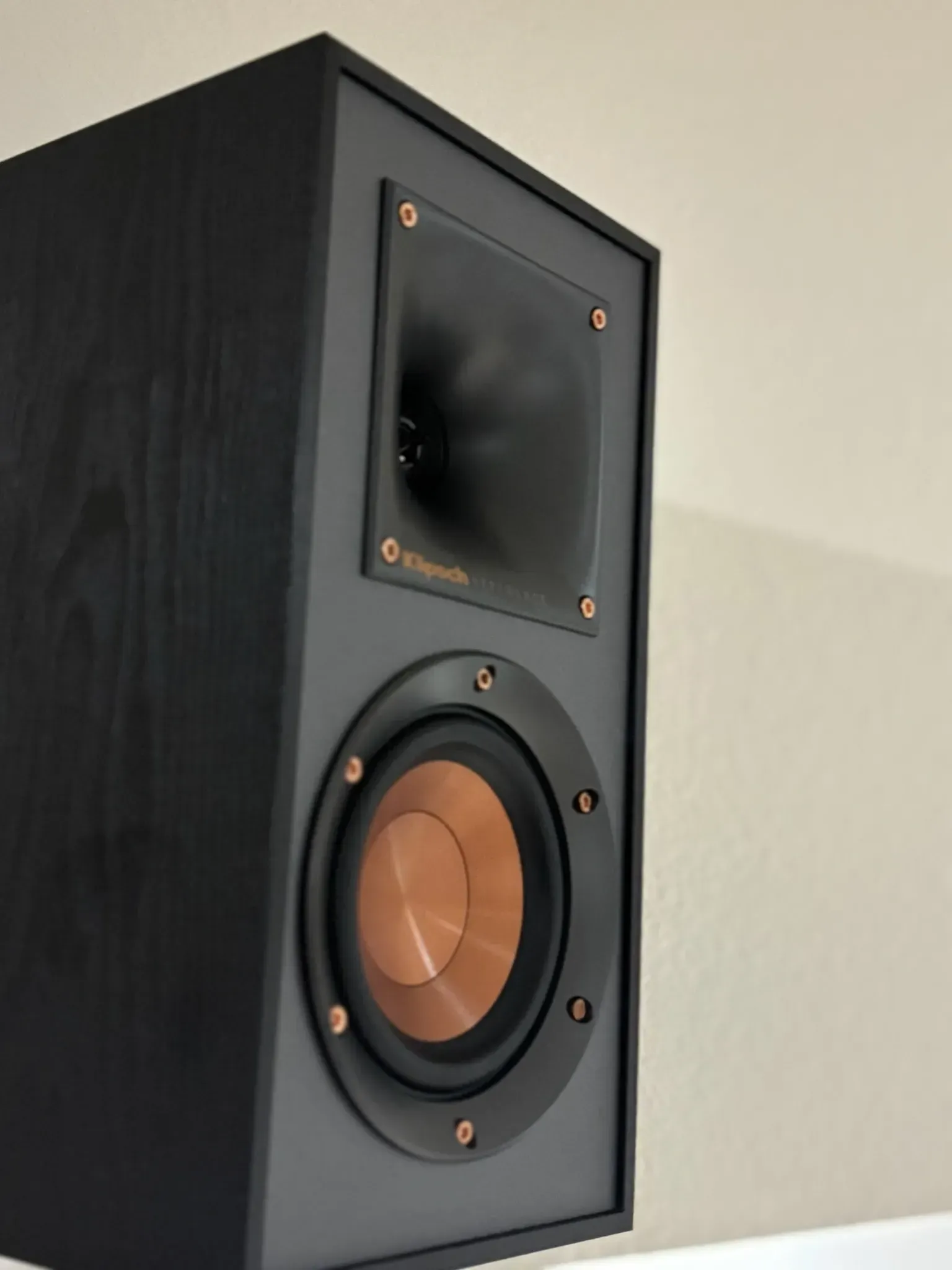 A black bookshelf speaker with a signature copper-colored woofer and a rectangular horn-loaded tweeter.