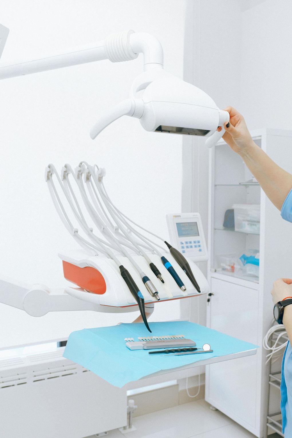 Dental exam room with chair, overhead light, and a person adjusting the lamp