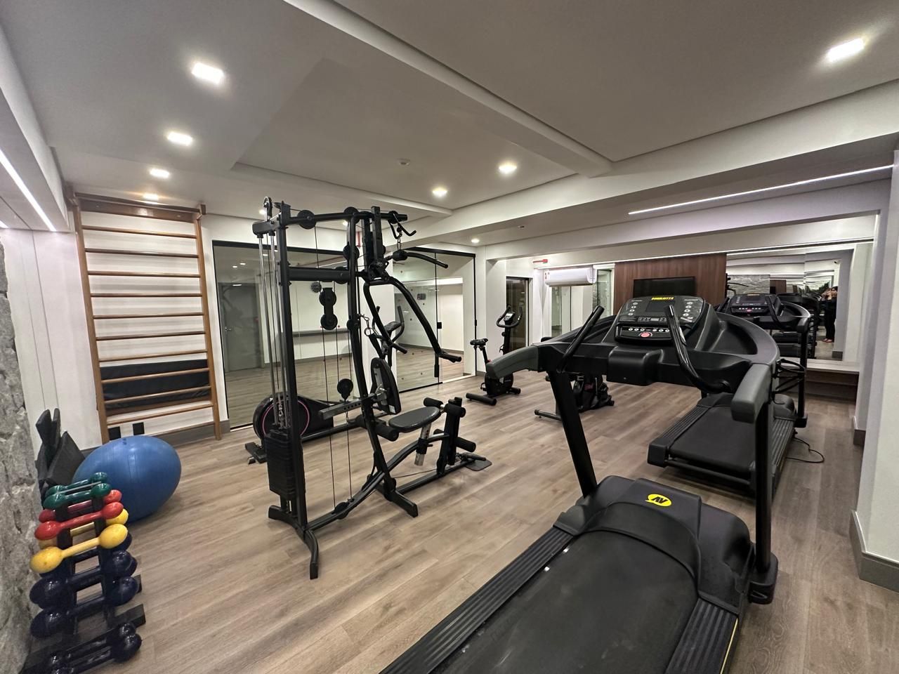 A gym with a treadmill , dumbbells , and other exercise equipment.