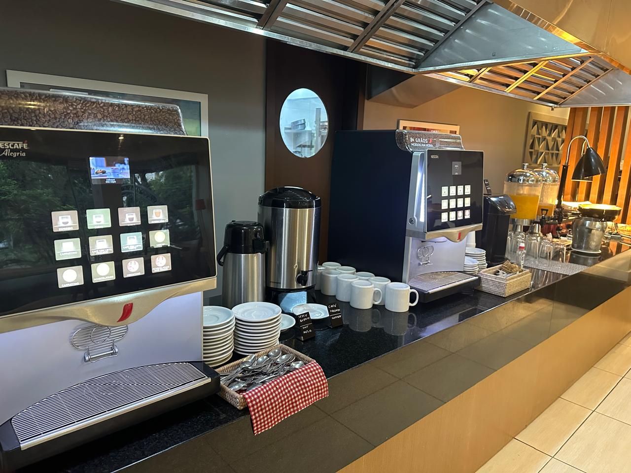 A restaurant with a lot of coffee machines and cups on the counter.