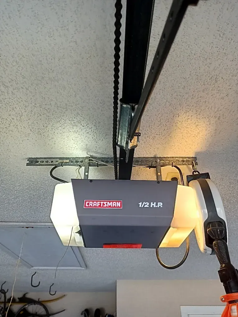 A Craftsman 1/2 HP garage door opener mounted to a ceiling with its interior lights turned on.