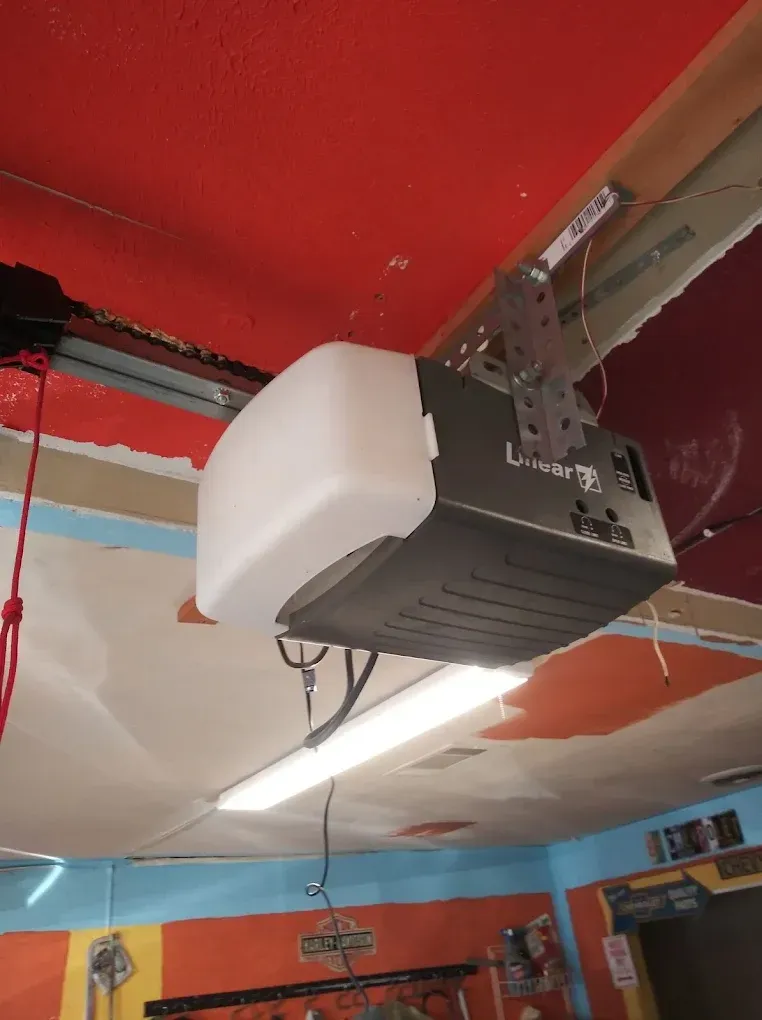 A white and black garage door opener mounted to a ceiling in a room with painted orange and blue walls.