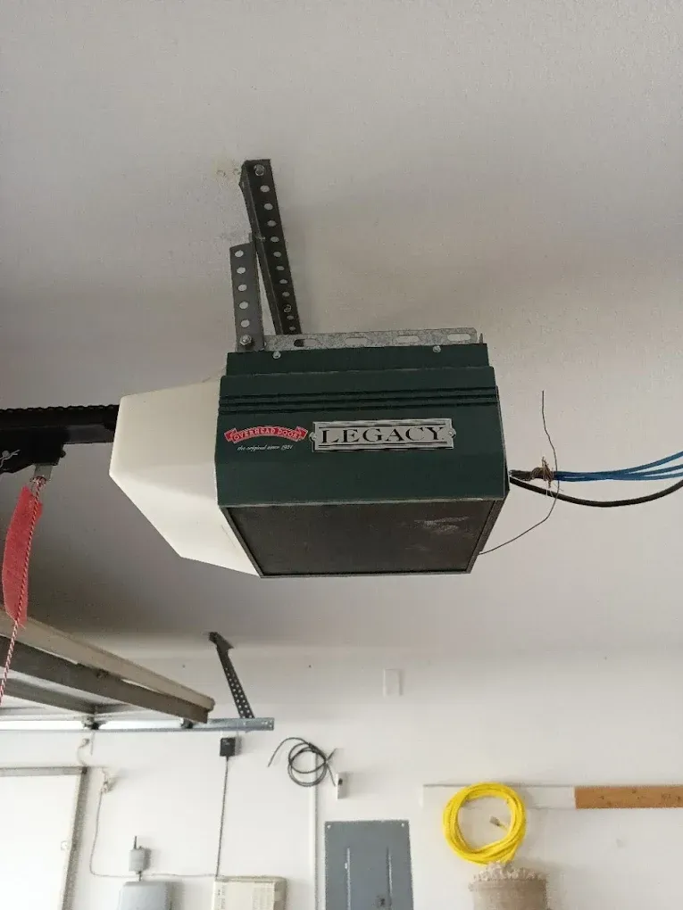 A green and white Chamberlain garage door opener motor is mounted to a residential garage ceiling.