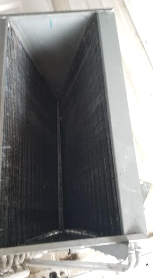 A close up of a dirty air conditioner coil on a white surface.