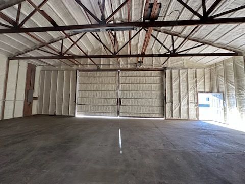 Empty warehouse interior with exposed beams, insulated walls, and concrete floor