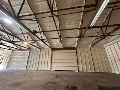 Empty warehouse interior with metal trusses, insulated walls, and a concrete floor