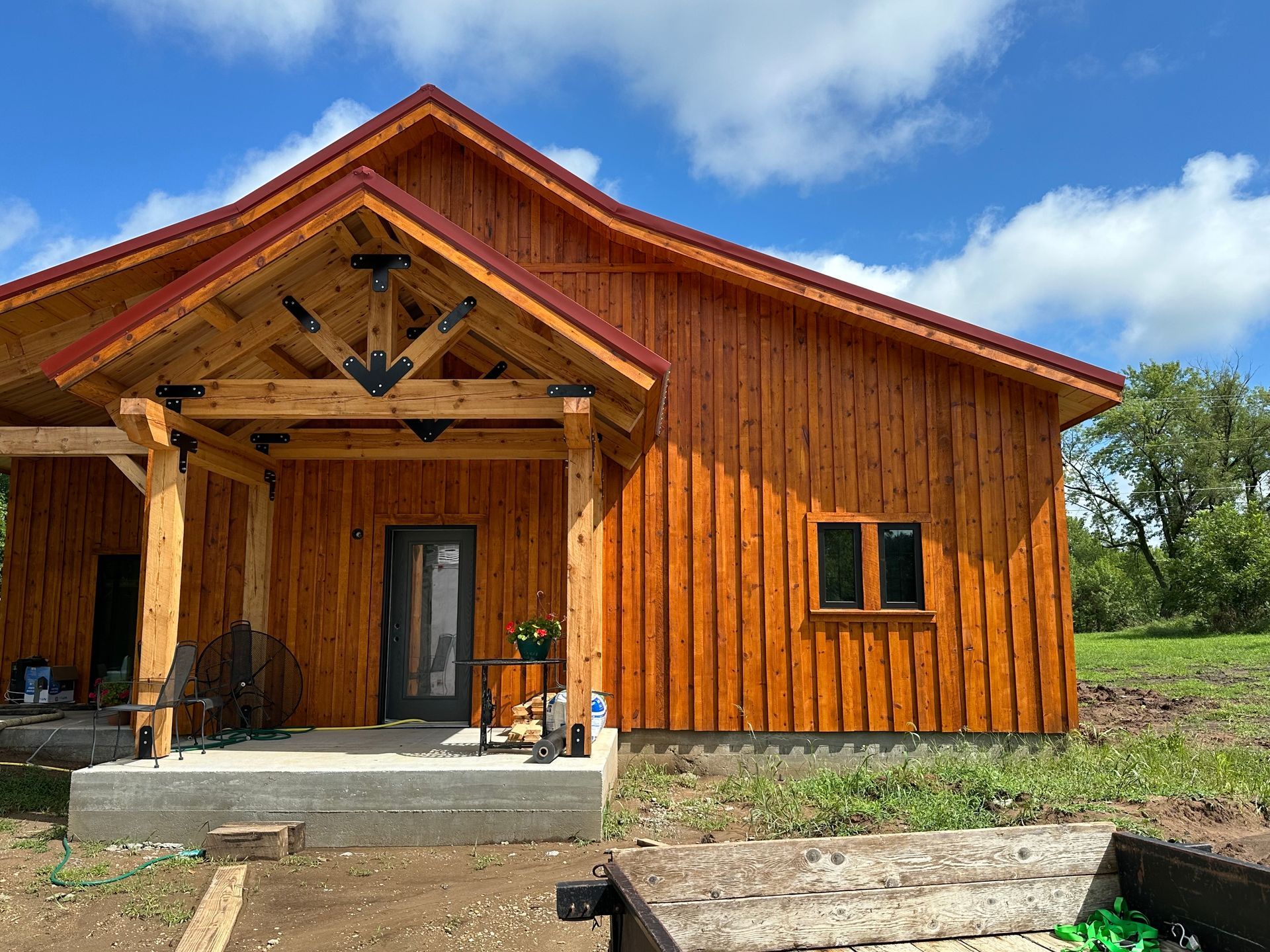 Rustic orange wooden cabin with a covered porch under a blue sky