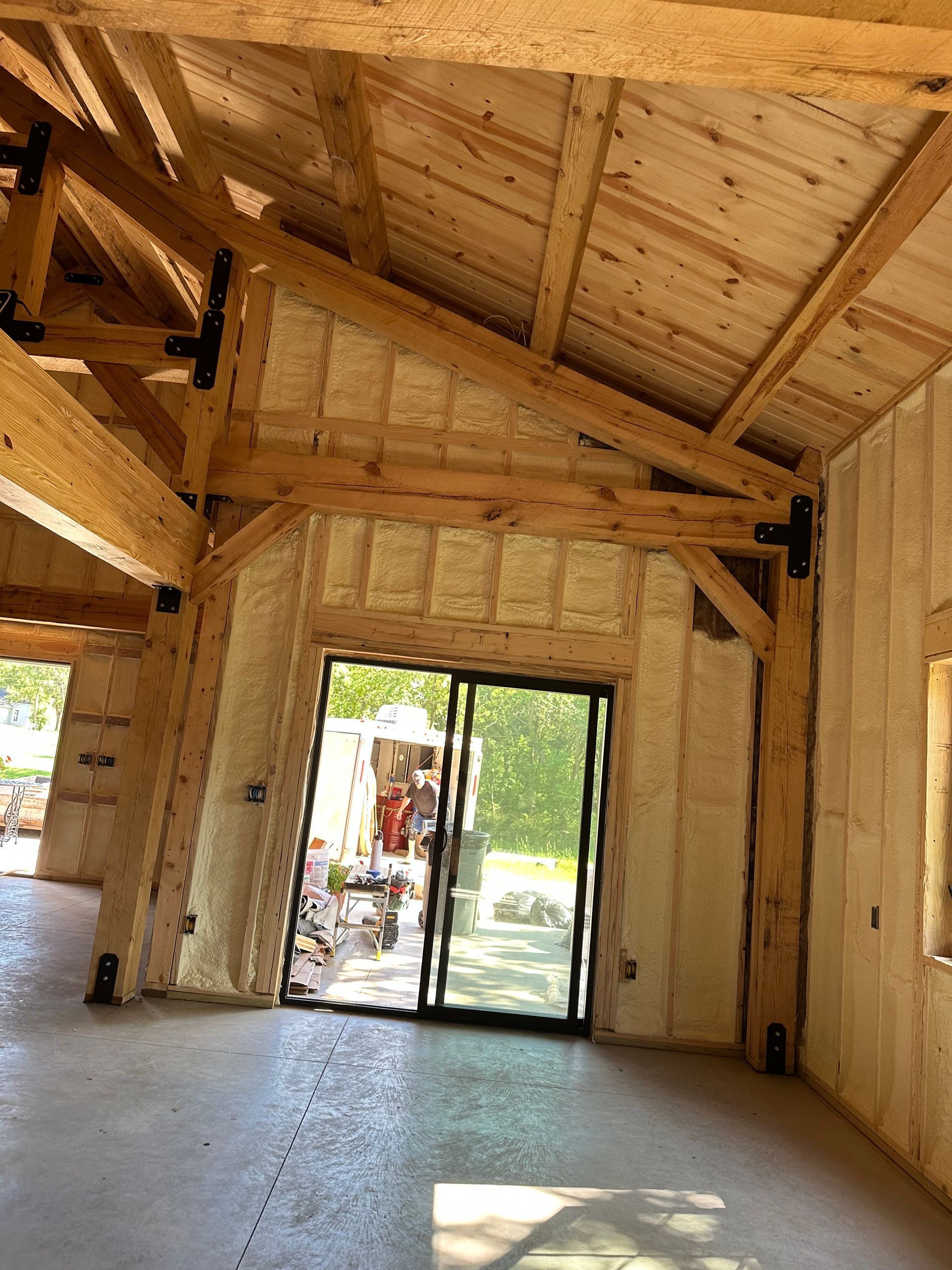 Wood-framed room interior with high vaulted ceiling and a glass door opening to the outside