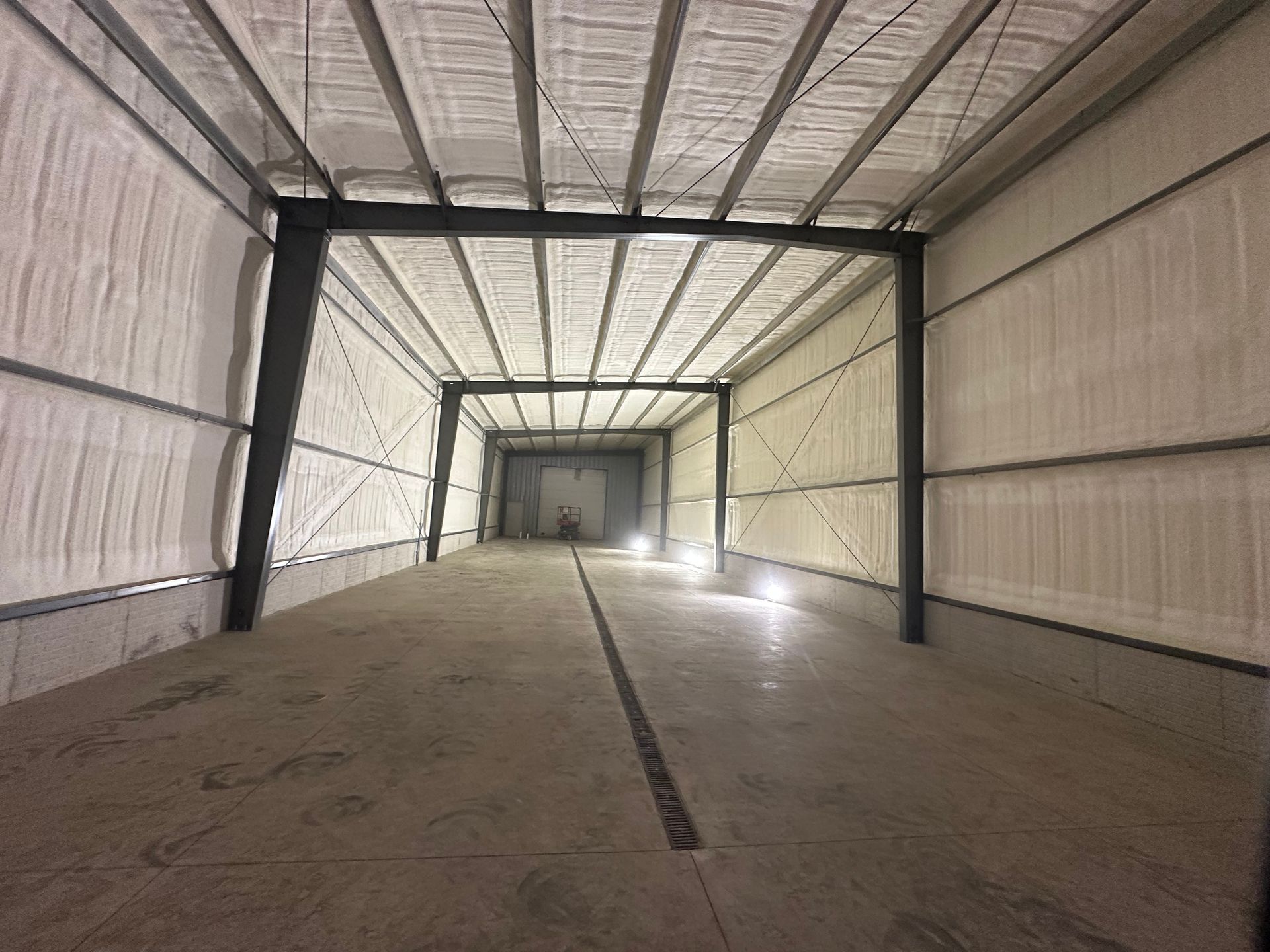 Empty industrial warehouse interior with metal walls, exposed beams, and a concrete floor