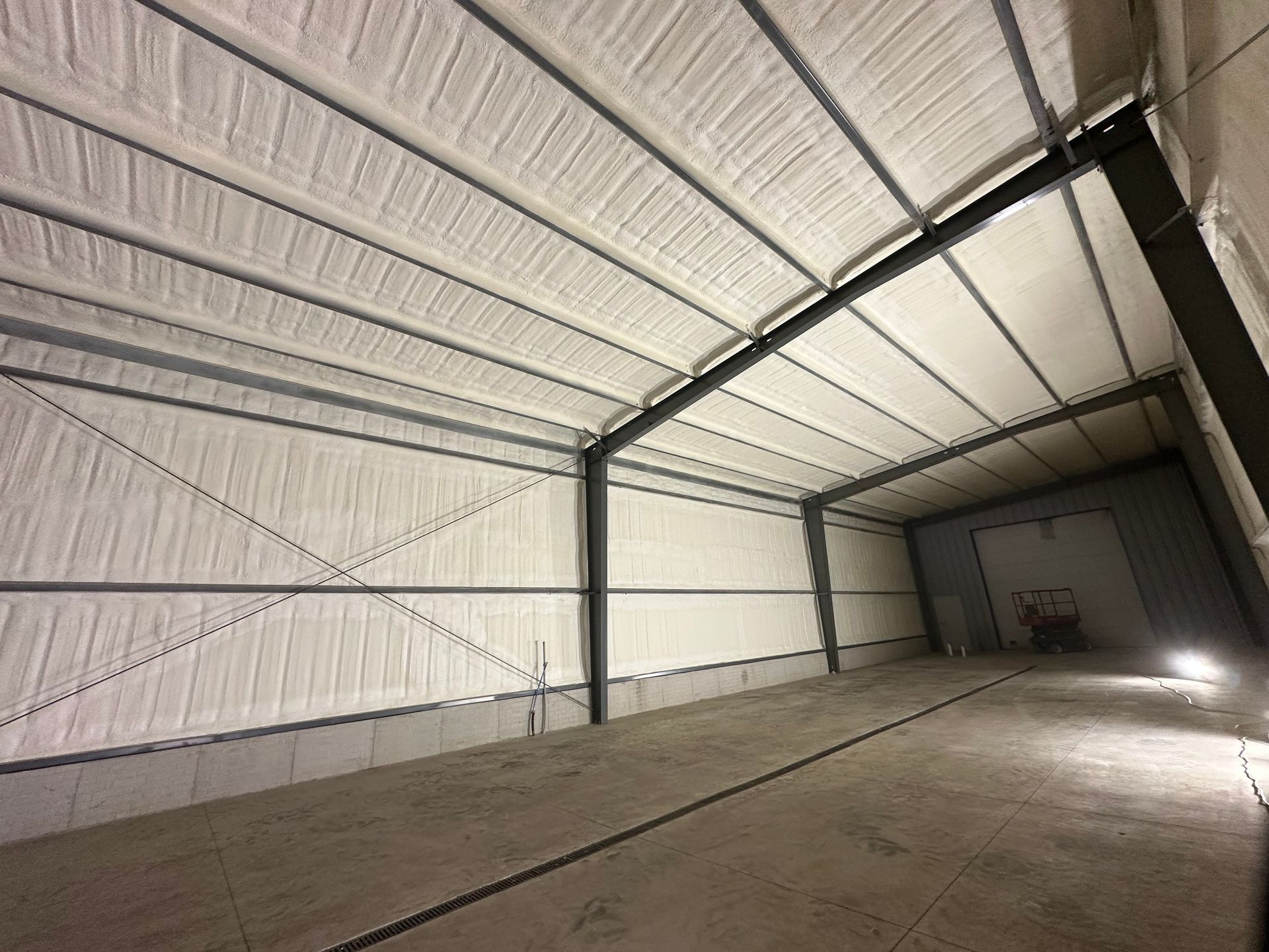 Empty metal warehouse interior with corrugated walls, exposed beams, and a concrete floor