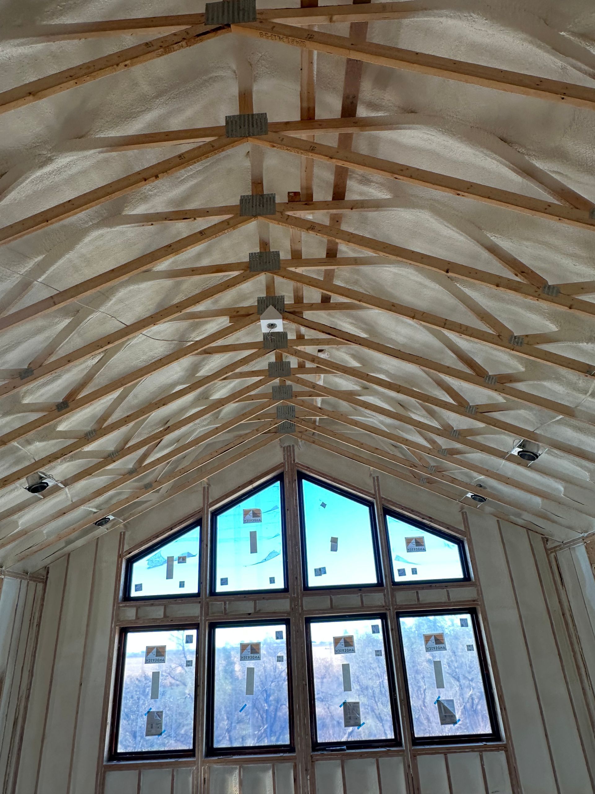 Vaulted wooden ceiling with exposed beams above a large window wall in a bright interior.