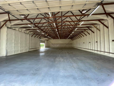 Empty warehouse interior with exposed roof trusses and a concrete floor