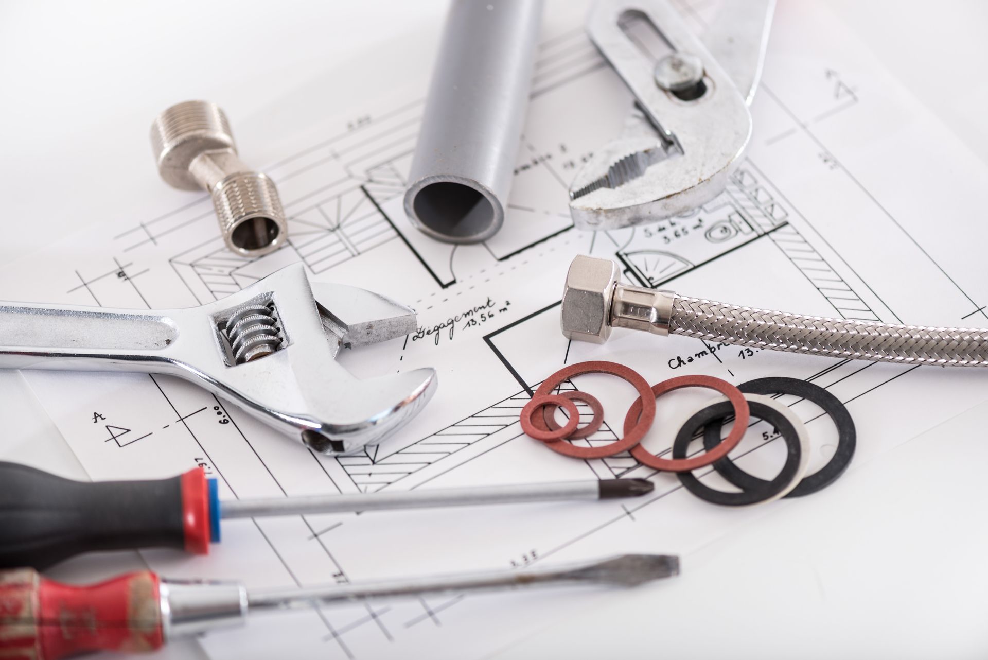 Plumbing tools and fittings laid out on top of technical drawings for a repair project.