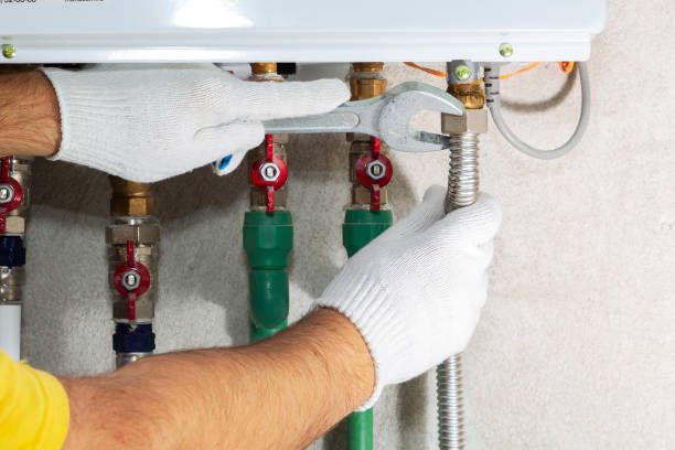 Close-up of hands using a wrench to tighten a pipe connection in a plumbing system.