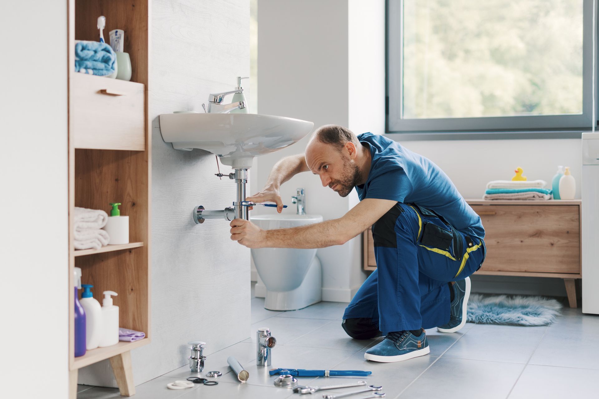 Professional plumber installing a bathroom sink and pipes, using water pump pliers. Professional plumber installing a bathroom sink and pipes, using water pump pliers.