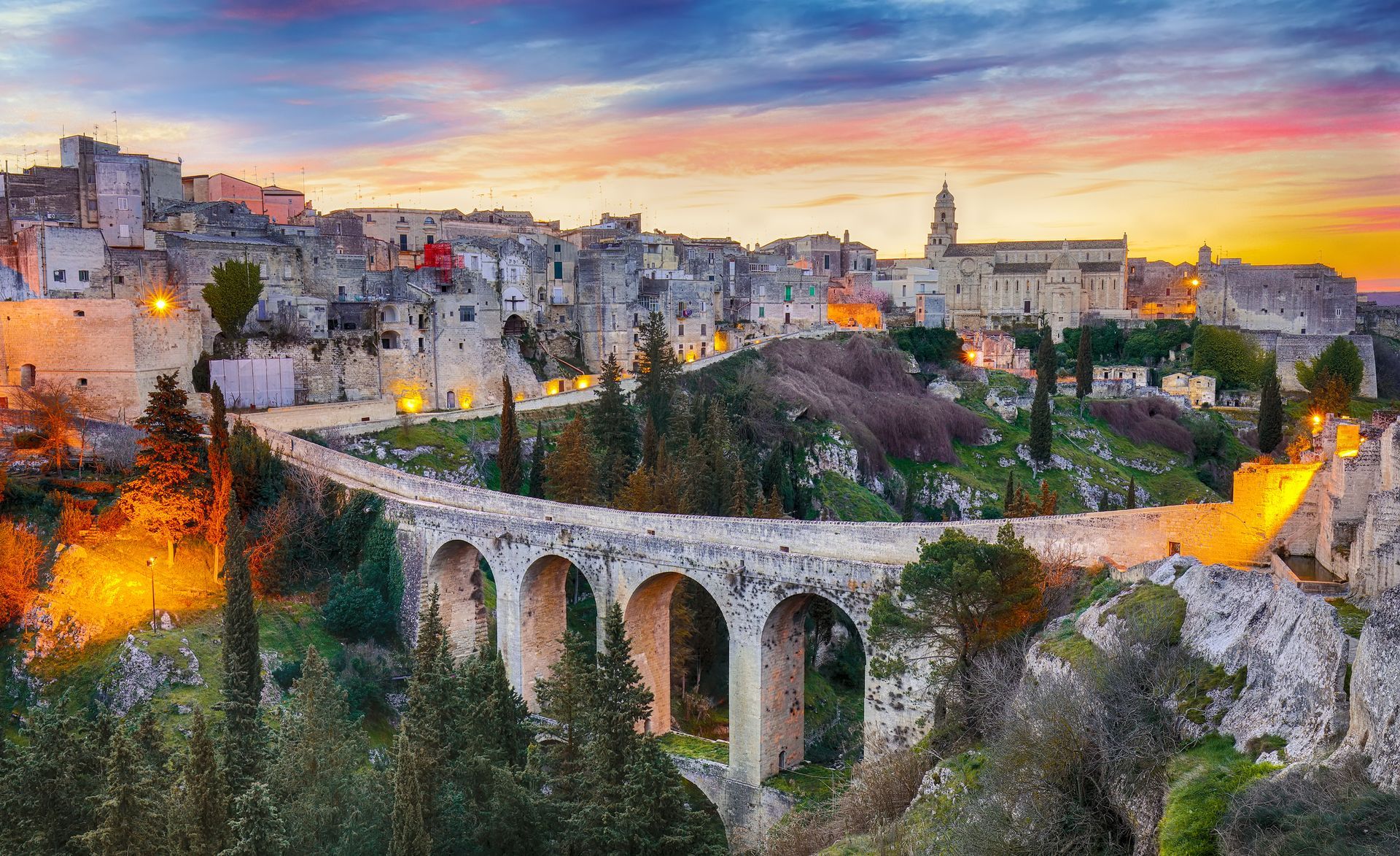 Una veduta aerea di una città al tramonto con un ponte in primo piano.