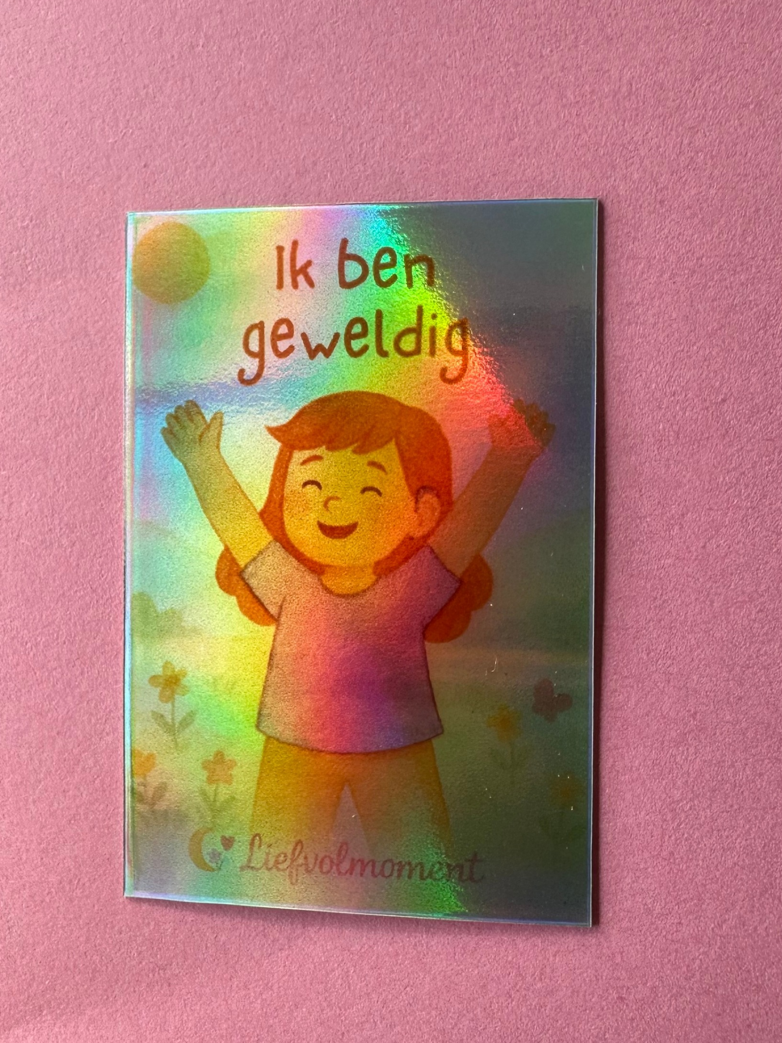 Een holografische sticker met een afbeelding van een persoon die zijn armen in vreugde omhoog steekt onder de zon. De tekst luidt: 